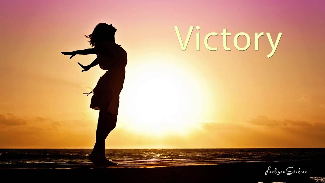 A woman on a beach at sunrise with her head thrown back, saying "Victory"