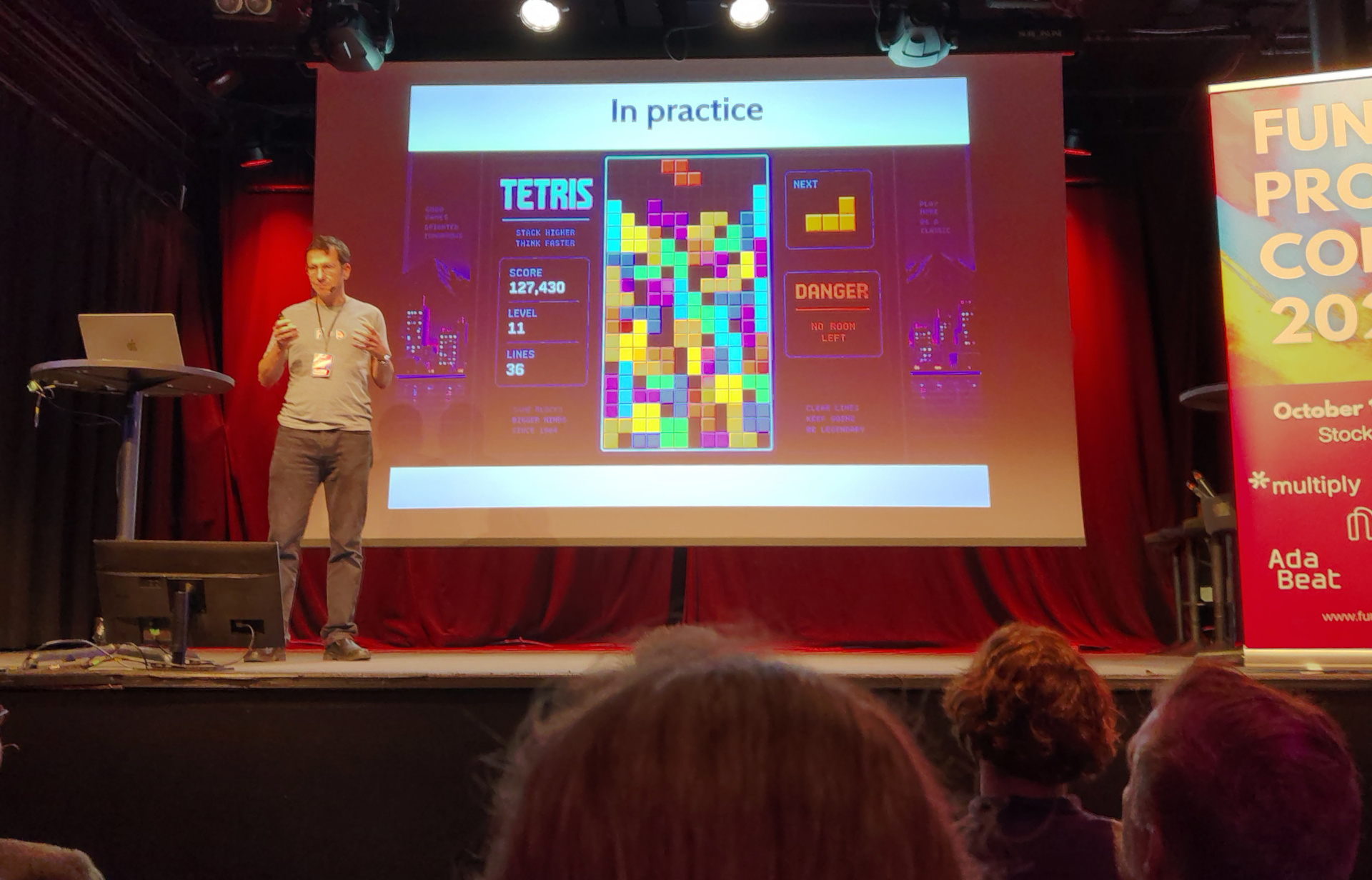 Вот эта катастроф! Eric presents a slide labelled "In practice", showing a game of Tetris about to be lost